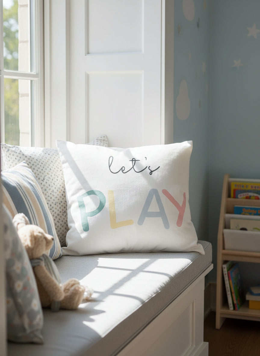 White pillowcase with 'Let's Play' text on a wooden floor